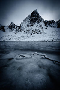 Scenic view of frozen lake against snowcapped mountains against sky