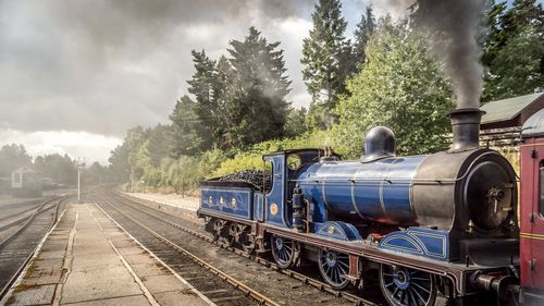 Train by railroad tracks against sky