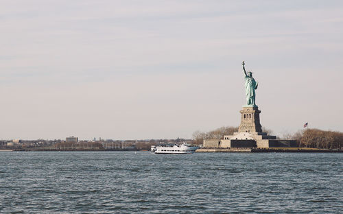 Statue of liberty by hudson river against sky