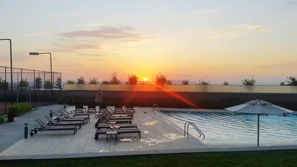 sunset, sky, sun, sunlight, orange color, nature, scenics, tranquility, cloud - sky, tranquil scene, outdoors, grass, chair, beauty in nature, no people, absence, empty, cloud, landscape, built structure