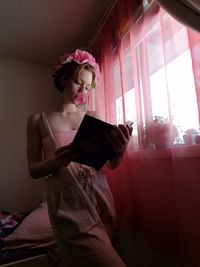 Woman looking through window at home