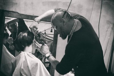 Barber cutting hairs of boy at salon