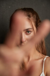 Young tender female reaching out hand towards camera on gray background in studio