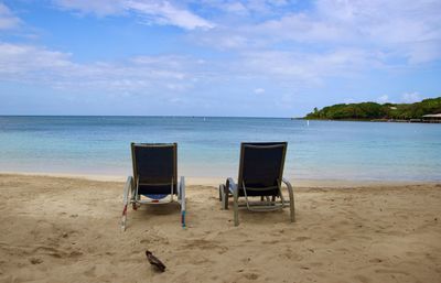 Deck chairs on beach against sky