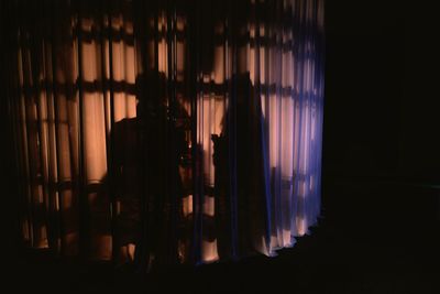 Rear view of woman standing by window at home