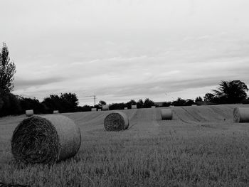 Hay bales on field against sky