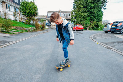 Full length of boy riding skateboarding on road