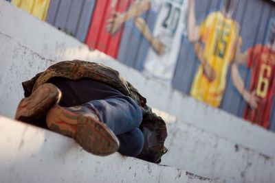 Homeless man sleeping on steps against graffiti wall