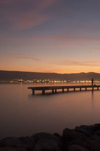 Silhouette bridge over river against sky at sunset
