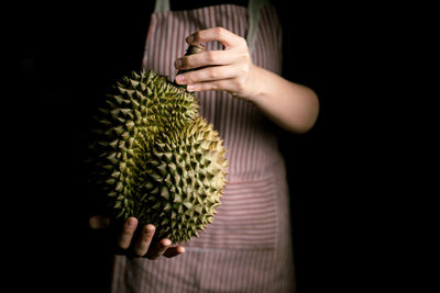 Midsection of person holding ice cream against black background