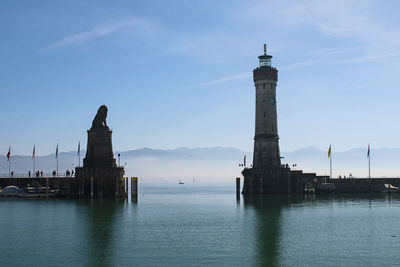 Lighthouse by sea against sky