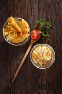 Raw pasta and tomato on table