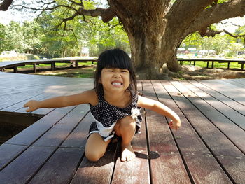 Close-up of cute girl crouching on plank in park