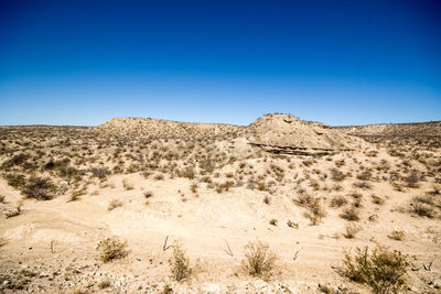 Scenic view of desert against clear blue sky