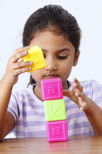 Girl adjusting toy blocks at table in home