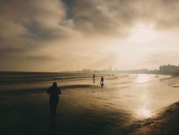 Rear view of silhouette people walking on beach