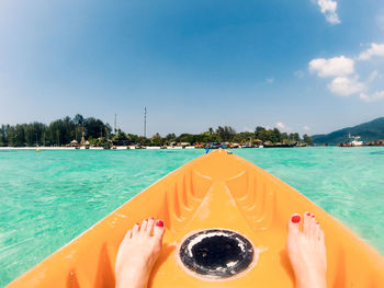 Low section of person in sea by swimming pool against sky