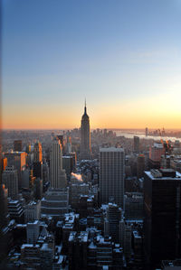 Mid distance of empire state building amidst cityscape against sky during sunset