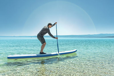 Side view of mature man paddleboarding on lake