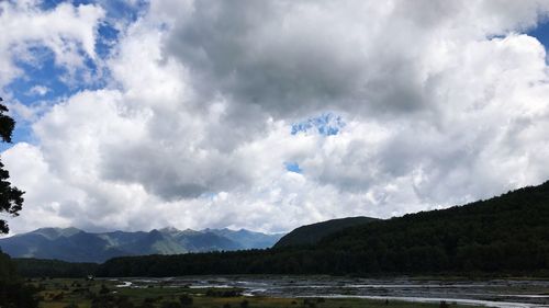Scenic view of mountains and river against cloudy sky