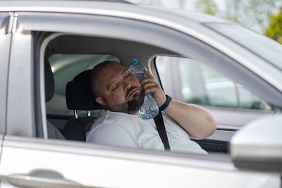 Side view of man using mobile phone while sitting in car