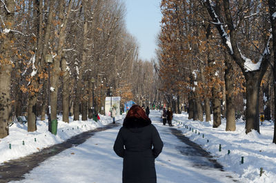 Rear view of woman standing on snow covered land