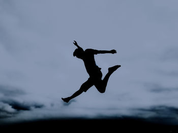 Silhouette man jumping against sky