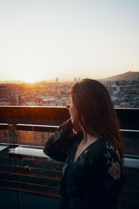 Woman looking at city at sunset