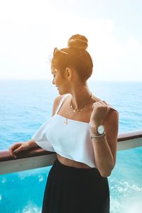 Woman standing by swimming pool against sky