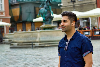 Man looking away while standing against built structure