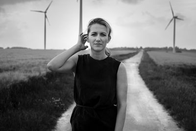 Portrait of beautiful young woman standing on country road