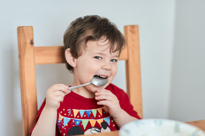 A boy is having fun at the breakfast table eating oatmeal