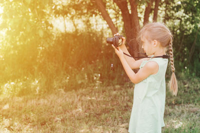 Side view of girl standing by tree