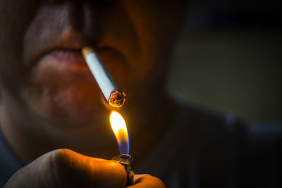 A man lights a cigarette from a lighter at night. macro photo close-up