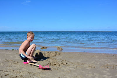 Sweet blond boy with  builds a sand castle in the sand on the beach in front of the sea