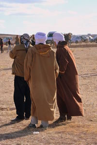 Rear view of people walking on field