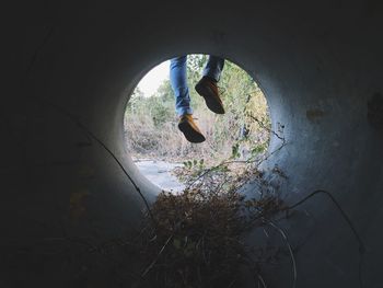 Low section of person seen through concrete pipe