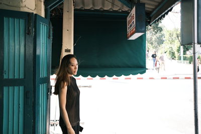 Portrait of smiling woman standing against built structure