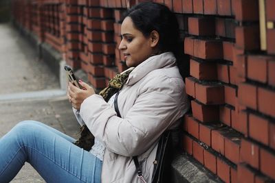 Mid adult woman using phone on footpath