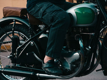 Low section of man sitting on motorcycle outdoors