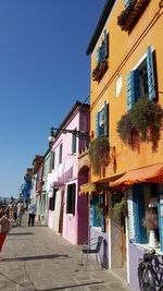 Street amidst buildings against blue sky