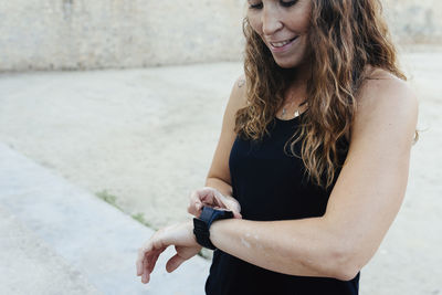 Young woman setting her watch before practicing urban crossfit.
