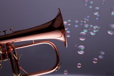 Close-up of bubbles emitting from trumpet against wall