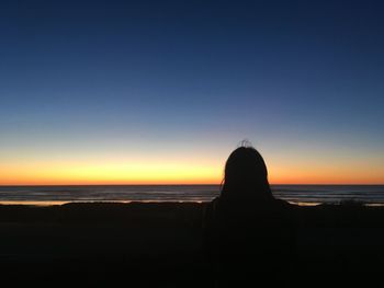 Silhouette man on beach against sky during sunset