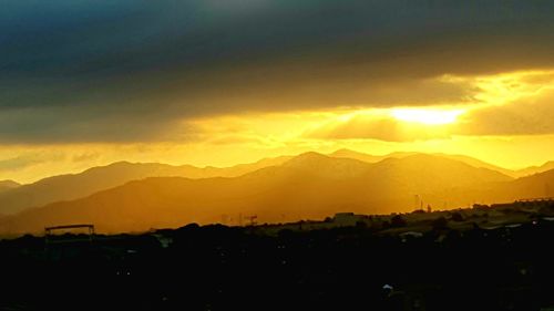 Scenic view of silhouette mountains against orange sky