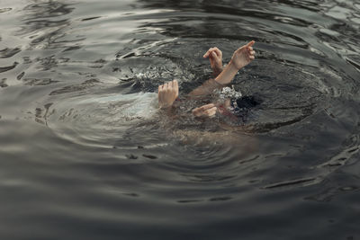 From above of crop anonymous travelers with raised arms swimming in pure water during trip