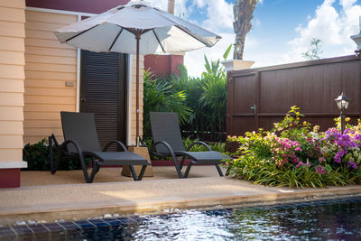 Chairs and tables by swimming pool against sky