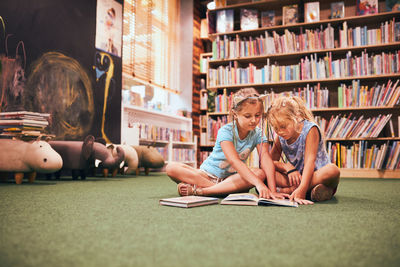 Two schoolgirls reading books in school library. primary school students. back to school