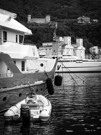 Boats moored in harbor with houses in background
