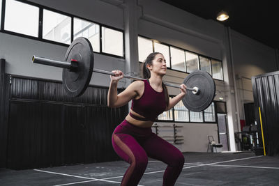 Female athlete exercising with barbell at health club